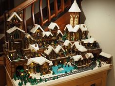 a christmas village is displayed on top of a table in front of a stair case