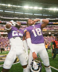 two football players standing on the field with their arms around each other's shoulders