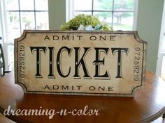 a wooden sign that says admit one ticket on top of a table in front of windows