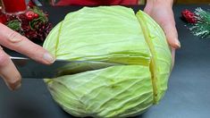 a person cutting up a cabbage on top of a table with christmas decorations behind them