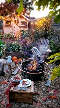 an outdoor fire pit in the middle of a garden with lots of food on it