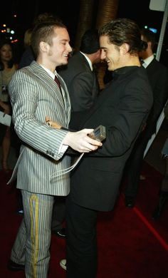 two men in suits standing next to each other on a red carpet at an event