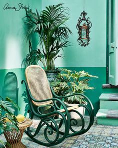 a rocking chair sitting on top of a tiled floor next to a potted plant