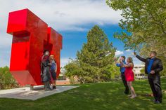 some people are standing in front of a red sculpture