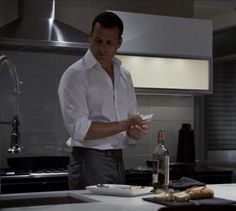 a man standing in a kitchen holding a knife and looking at something on the counter