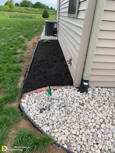 a small garden bed with rocks and gravel in front of a house on the grass