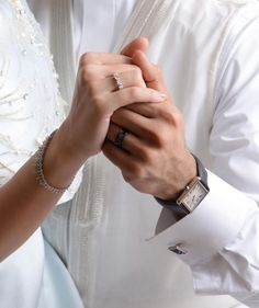 a man and woman holding hands while wearing wedding rings