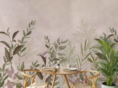 two chairs and a table in front of a wall with plants on it