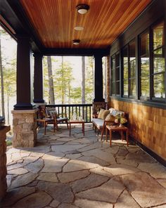 an outdoor covered porch with chairs and tables