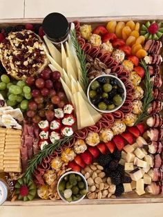 an assortment of cheeses, crackers, fruit and nuts in a wooden tray