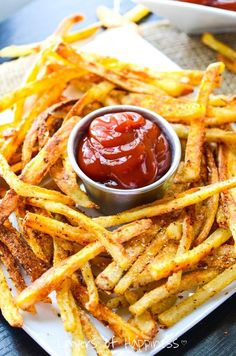 french fries with ketchup and mustard on a white plate next to dipping sauce