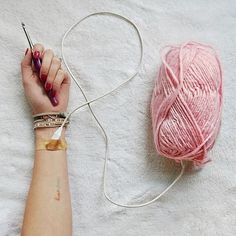 a woman's arm with a ball of yarn and a crochet hook