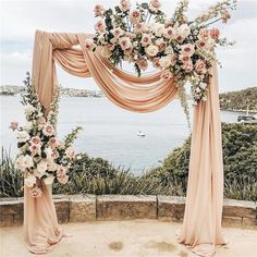 an outdoor wedding setup with flowers and draping on the top, overlooking the water