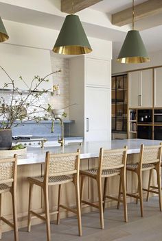 a kitchen with wooden chairs and an island in front of the countertop, along with two pendant lights hanging from the ceiling