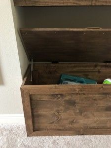 an open wooden box sitting on the floor next to a white wall and carpeted floor