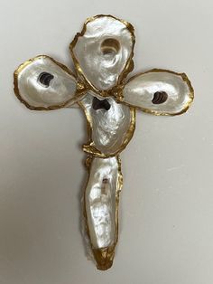 a cross made out of oyster shells on a white surface with gold trimmings