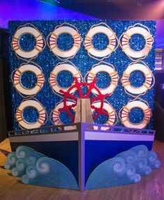 a boat with life preservers on it in front of a blue wall decorated with red and white circles