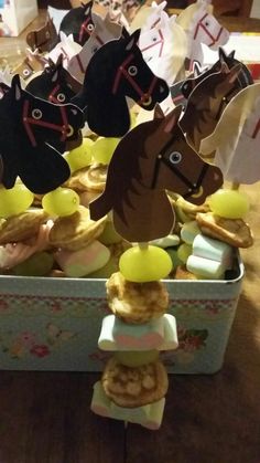 some paper horses are sitting on top of cookies in a tinker box with candy