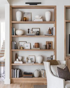 a living room filled with lots of furniture and shelves covered in vases on top of them