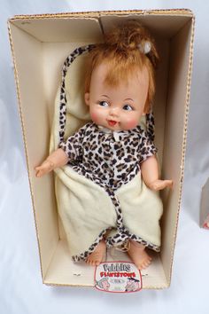 an old doll in a box with a leopard print robe on it's head