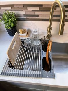 a kitchen sink with utensils and wooden spoons in the bottom rack next to it