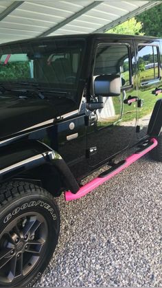 a black jeep with pink trim parked in a parking lot