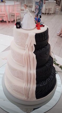 the wedding cake is decorated with black tires and white frosting, as well as a bride's dress