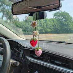 a car dashboard with a stuffed strawberry hanging from the dash board