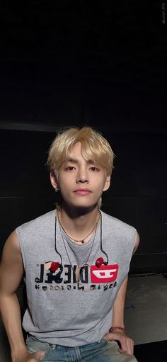 a young man sitting down in front of a black background with his hands on his hips