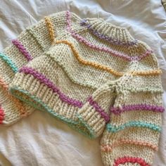 a knitted sweater laying on top of a bed