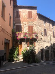 an old building with flowers growing on it's windows and balconies above the doorway