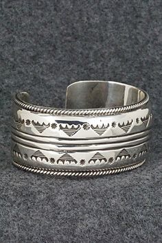 This stunning and substantial sterling silver bracelet was made by Navajo silversmith Emerson Delgarito. The inside is signed E. Delgarito.Size: 5 1/2" (will fit up to a 6 3/8" wrist)Gap: 7/8"Length: 1 1/8"Free shipping on all orders! We ship with USPS and always include tracking. All orders ship within a day of payment.Returns are accepted up to 30 days after you receive your order. Just send us a message. Our shop offers cash back or store credit. The item must be returned in new condition. Silver Artisan Bracelet, Untreated Sterling Silver Bracelet, Sterling Silver Southwestern Bracelet, Silver Untreated Cuff Bracelet Gift, Sterling Silver Southwestern Bracelet With Polished Finish, Southwestern Etched Bangle Jewelry, Southwestern Style Etched Bangle, Southwestern Silver Bangle Jewelry, Southwestern Style Polished Bangle