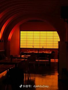 an empty room with tables and chairs in front of a window that is lit by red lights