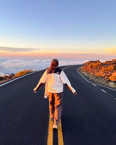 a woman walking down the middle of an empty road