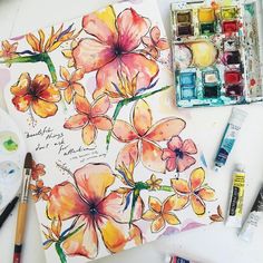 some watercolors and paint on a table with flowers