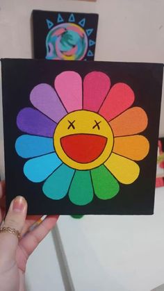 a person holding up a small card with an image of a flower painted on it