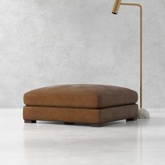 an ottoman with a lamp on top of it in front of a concrete wall and floor