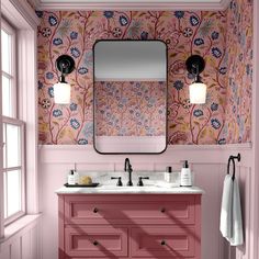 a bathroom with pink walls and floral wallpaper, two sinks and a large mirror