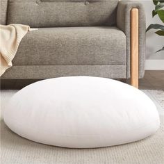 a large white pillow sitting on top of a floor next to a couch and chair