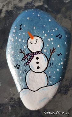 a painted rock with a snowman on it's face and music notes in the background