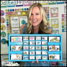 a woman holding up a blue tray with lots of different items on it in front of a bulletin board