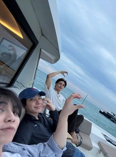 three people sitting on the back of a boat in front of an ocean and sky