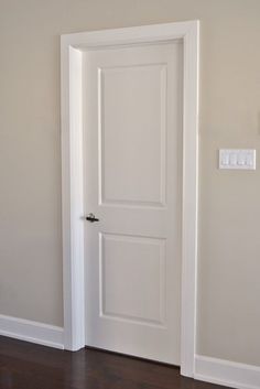 an empty room with a white door and wooden floor