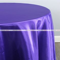 a purple table cloth on top of a wooden floor in front of a white wall