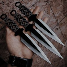 a person holding four knives in their hand with black handles and blades on each blade