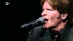 a man singing into a microphone in front of a black background with words on it