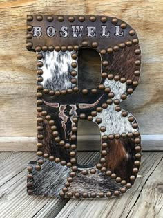 the letter b is made out of cowhide and metal rivets with beads