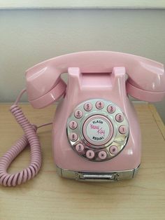 an old pink rotary telephone on a black surface