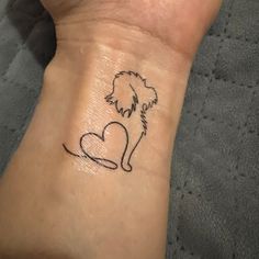 a small tattoo on the wrist of a person with a dog and heart in it