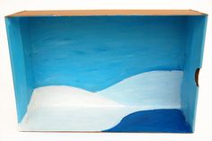 a blue box with white mountains painted on the outside and inside, in front of a white background